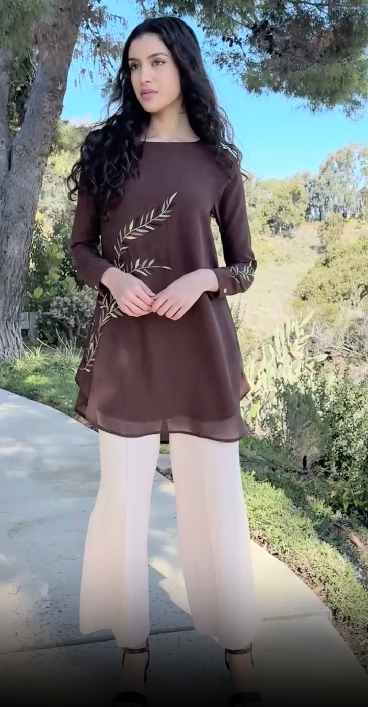 Woman outside wearing Baraka tunic in Cocoa with white pants and heels.