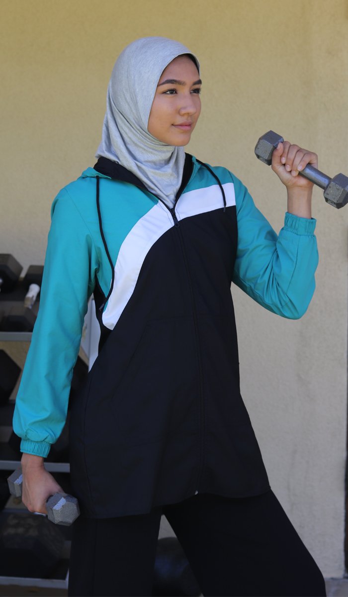 Woman wearing sports hijab in heather gray while lifting weights.