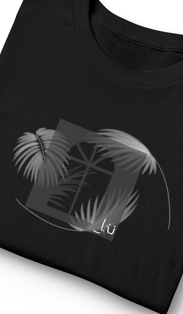 A close-up of a black t-shirt featuring a gray graphic print of a window framed by palm leaves, with Nakhl Arabic calligraphy near the bottom of the design.