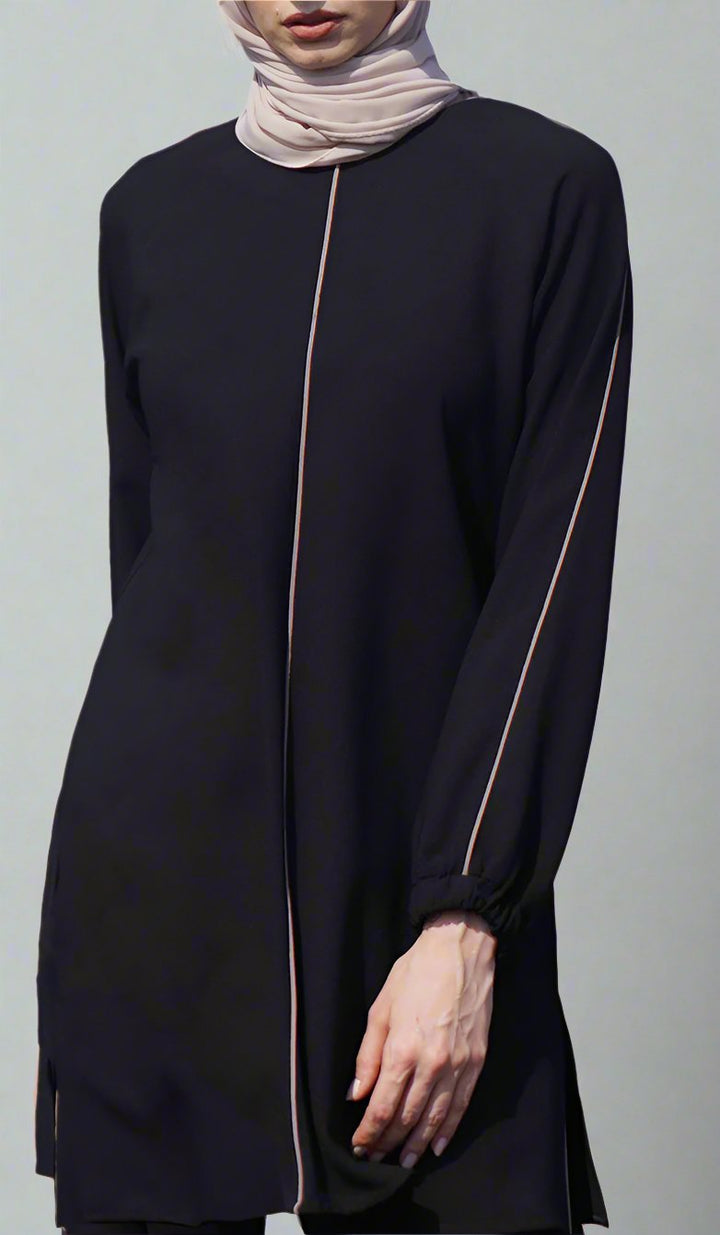 Woman wearing Abiyya tunic in Black/Cafe. 