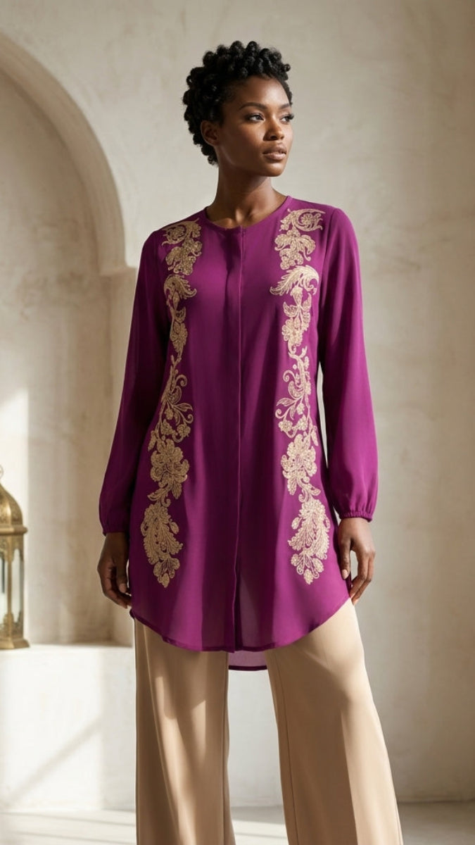 Woman wearing a purple embroidered top with beige pants in an indoor setting