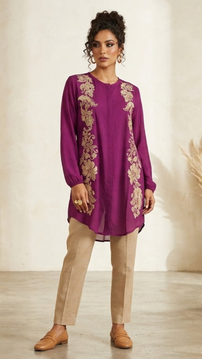 Woman wearing a purple embroidered dress with beige pants on a neutral background