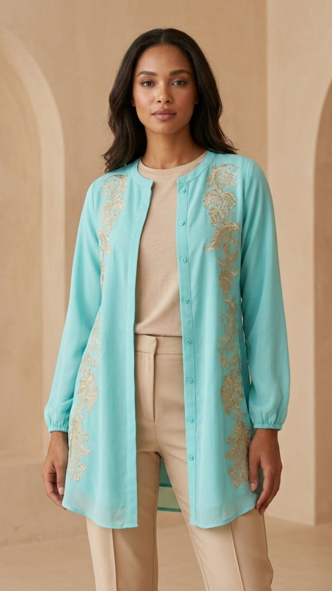 Woman wearing a light blue embroidered jacket in a beige archway setting