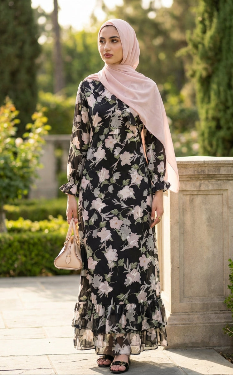 Woman in a floral dress and hijab standing in a garden setting