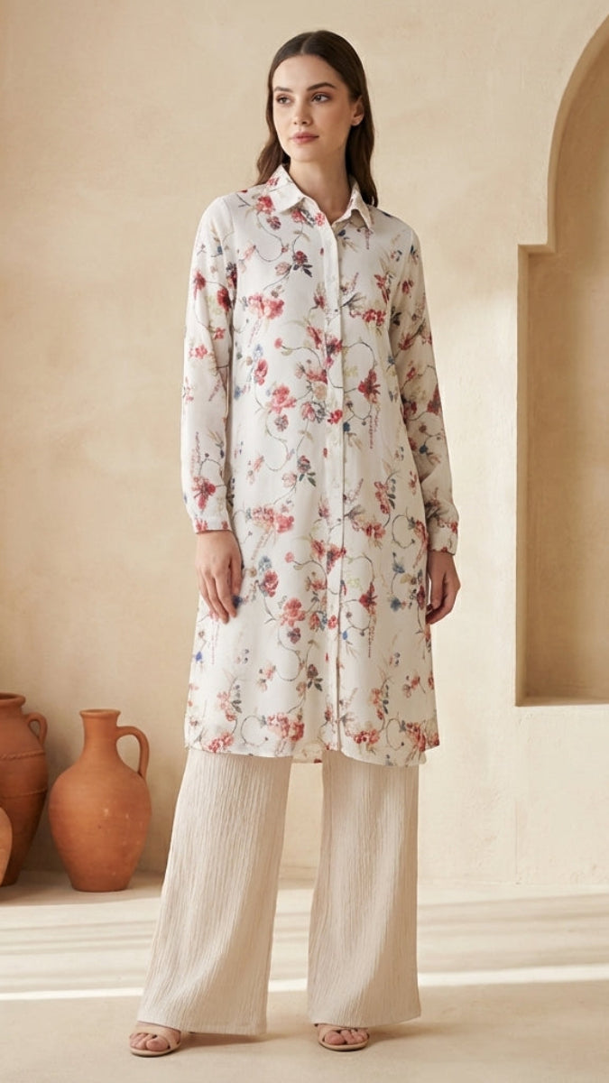 Woman wearing a floral outfit standing in a sunlit room with decorative vases.