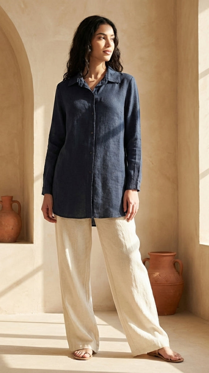 Woman in a blue shirt and beige pants standing in a sunlit room with decorative elements.