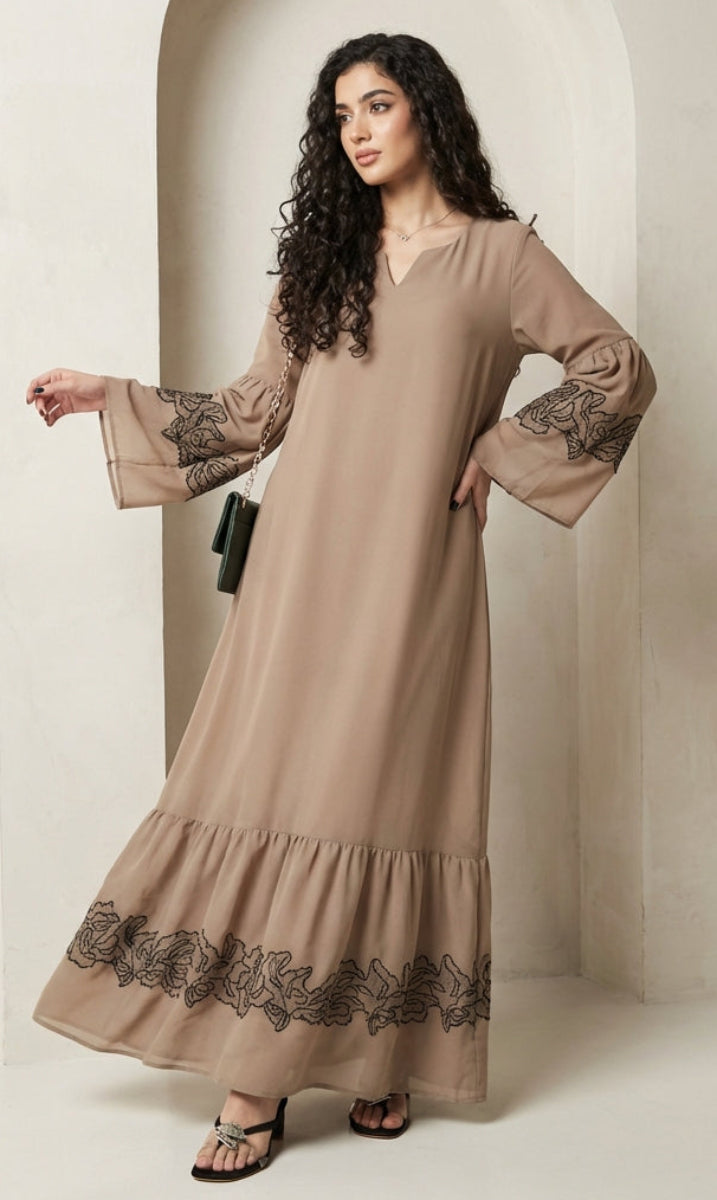 Woman wearing a beige long dress with lace details in an archway.