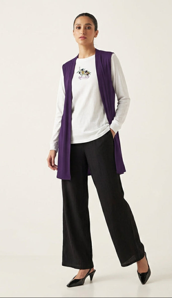 Woman wearing a white shirt, black pants, and a purple cardigan on a white background