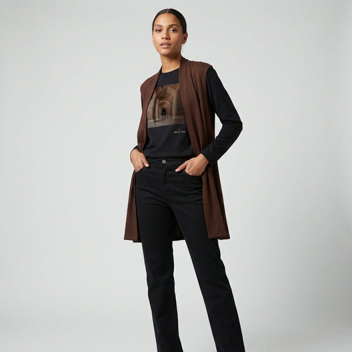 Person wearing a brown cardigan over a black shirt with a graphic design, standing against a plain background.