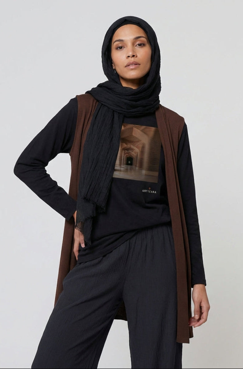 Woman wearing a black hijab, brown cardigan, and black pants on a white background