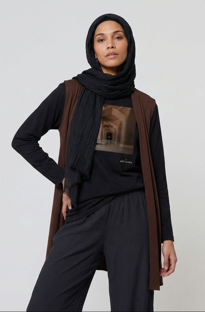 Woman wearing a black hijab, brown cardigan, and black pants on a white background