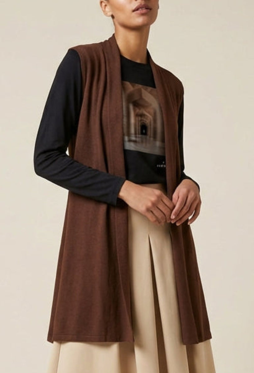 Woman wearing a brown cardigan and beige skirt against a beige background