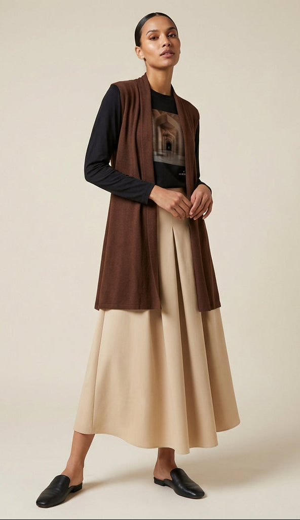 Woman wearing a brown cardigan and beige skirt against a beige background
