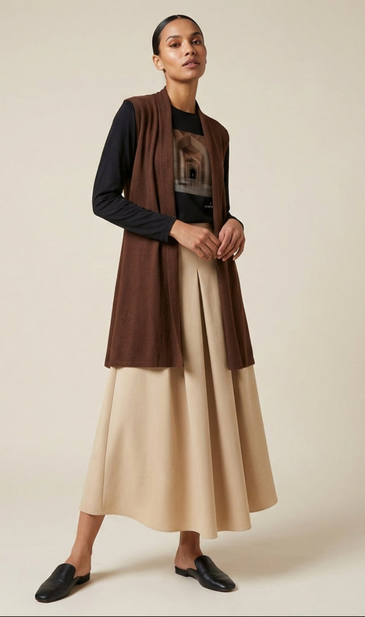 Woman wearing a brown cardigan and beige skirt against a beige background