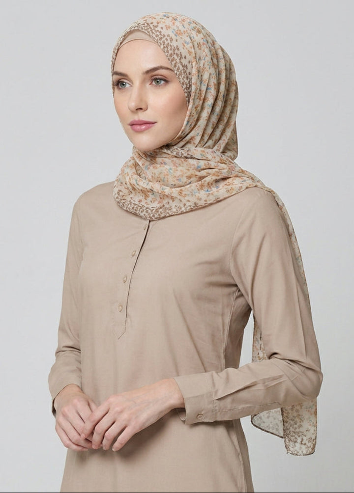 Woman wearing a beige hijab and shirt against a light gray background