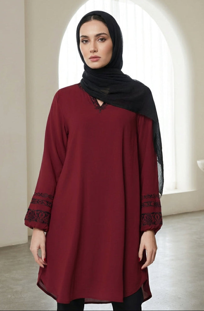 Woman wearing a red dress with black hijab in a minimalistic room.