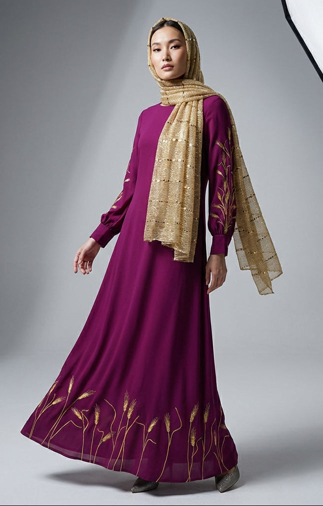 Woman wearing a long purple dress with gold embroidery and a matching headscarf in a studio setting.