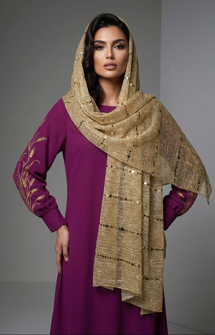 Woman wearing a purple dress with gold embroidery and a matching gold scarf against a gray background