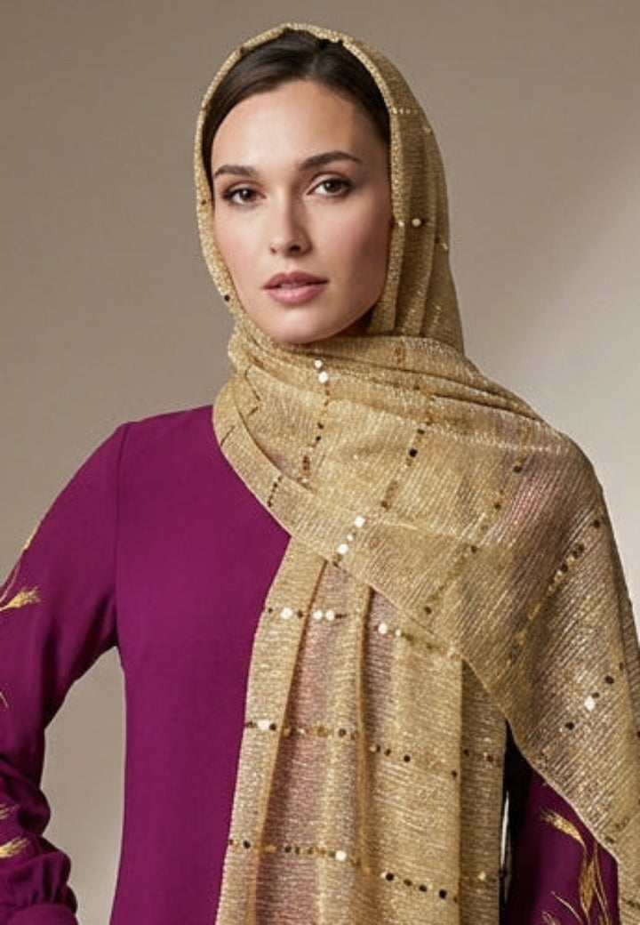 Woman wearing a purple dress with a gold scarf in a studio setting
