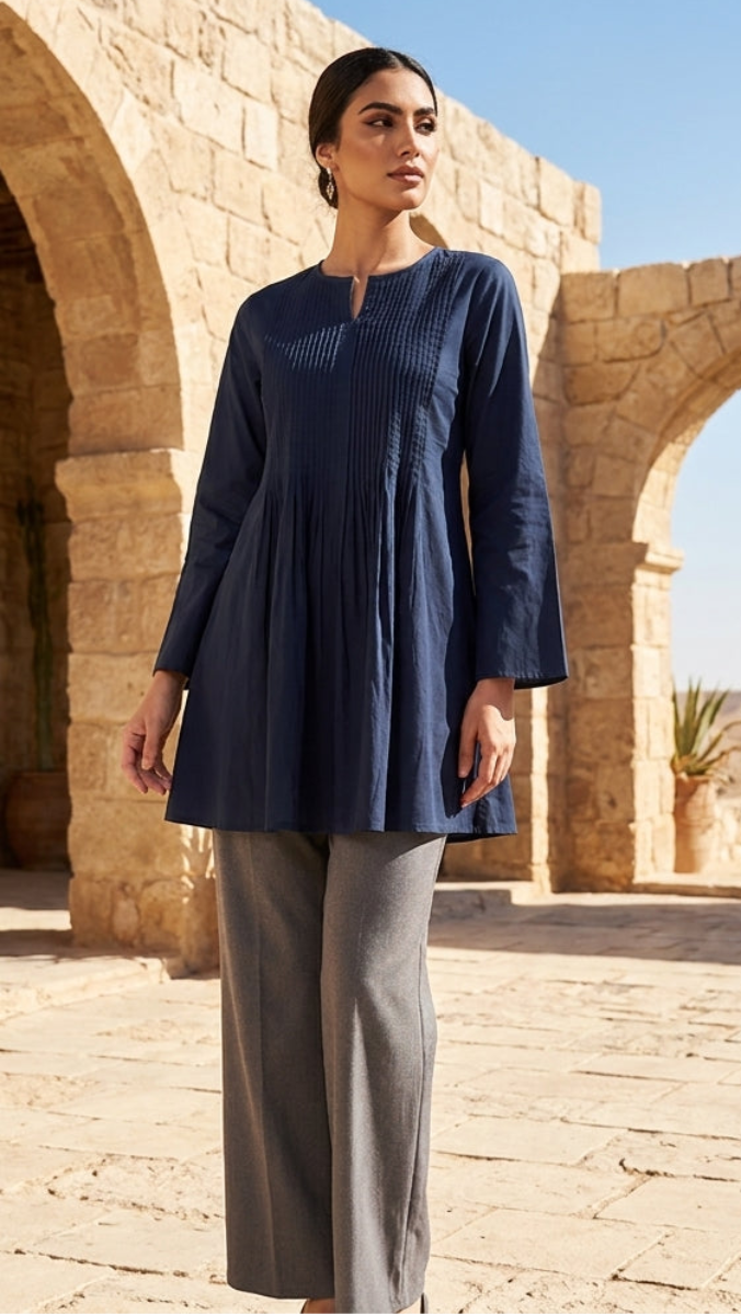 Woman in a blue dress standing in front of stone arches and desert landscape