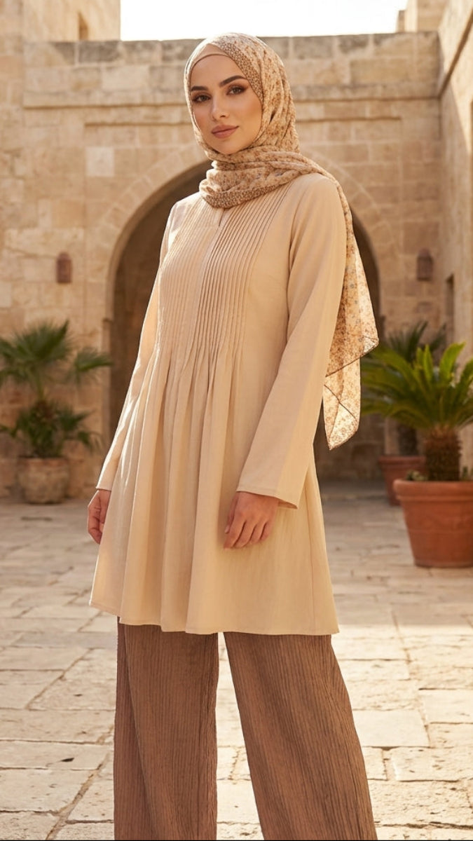 Woman in beige outfit standing in a stone courtyard with plants.