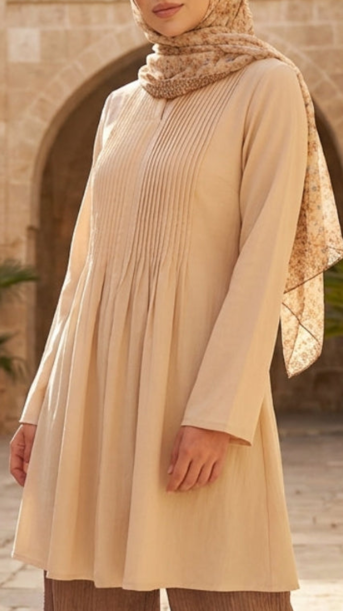 Person wearing a beige dress and headscarf in an outdoor setting