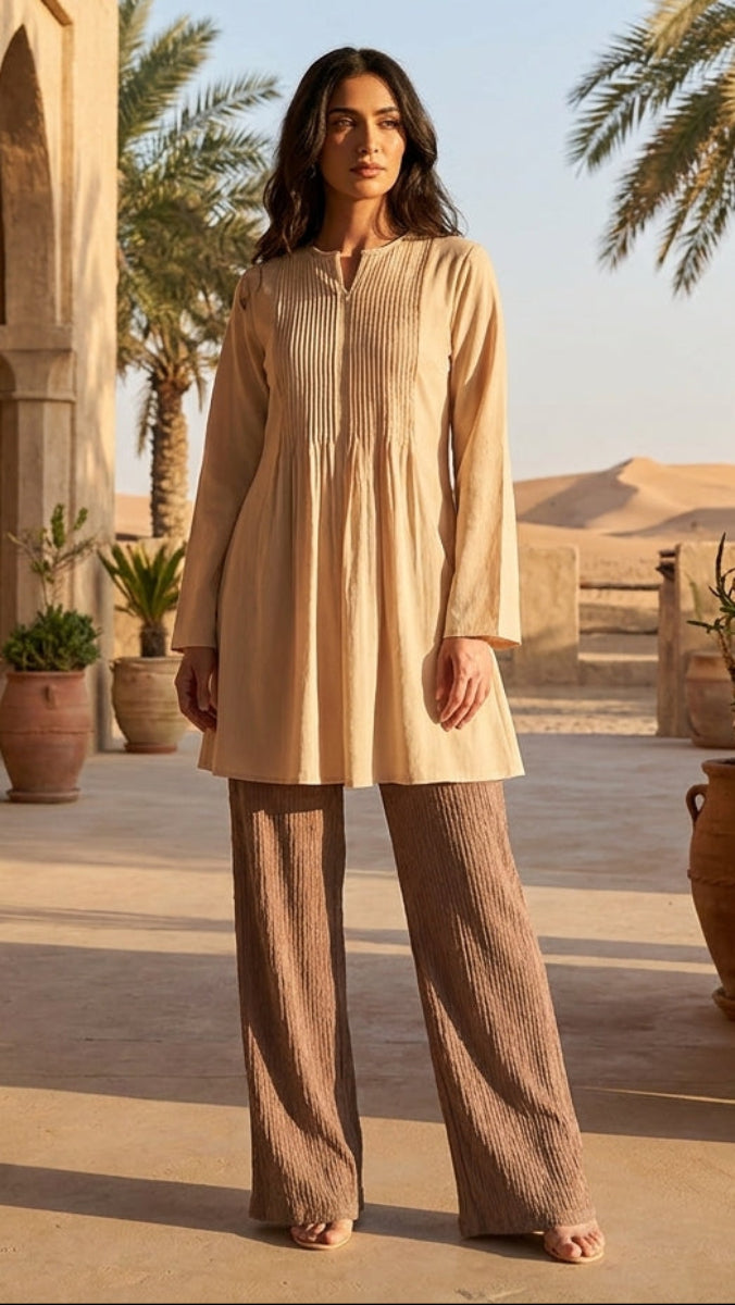 Woman standing in a desert setting with architectural elements and palm trees.