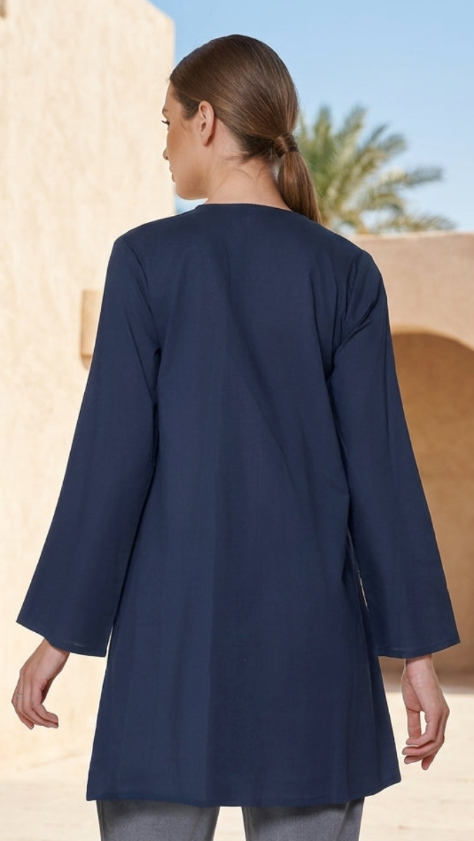 Woman wearing a navy blue coat in an architectural setting with arches and palm trees.