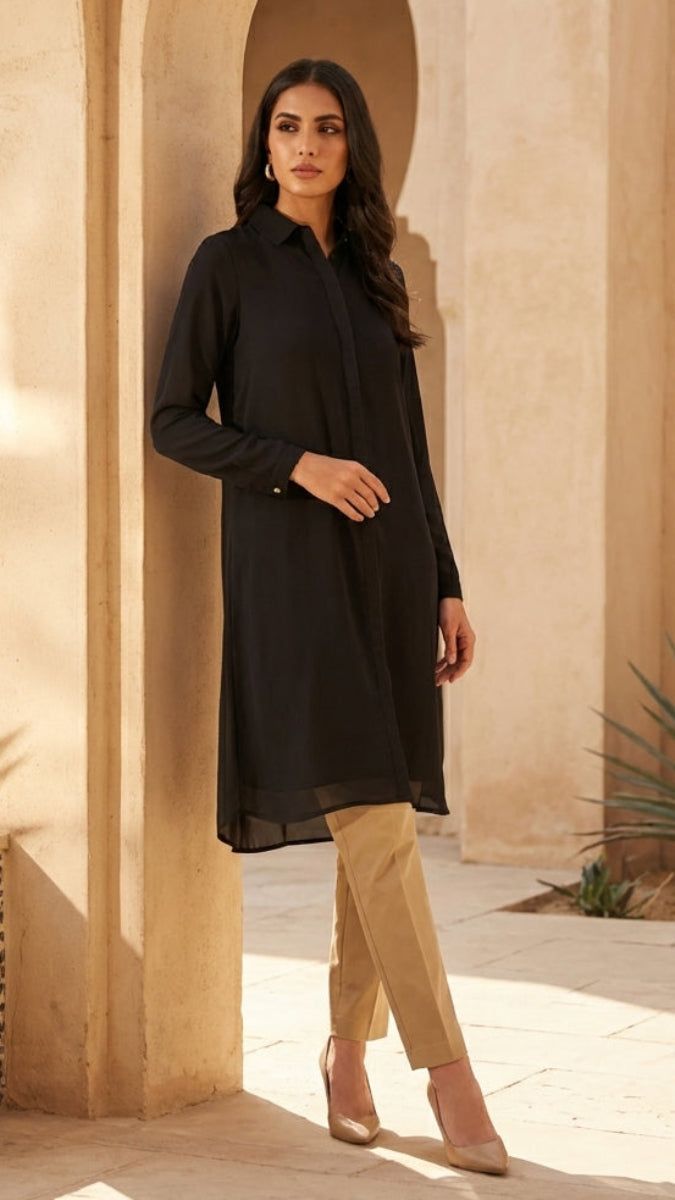 Woman in a black dress standing in a sunlit courtyard with arches and plants.
