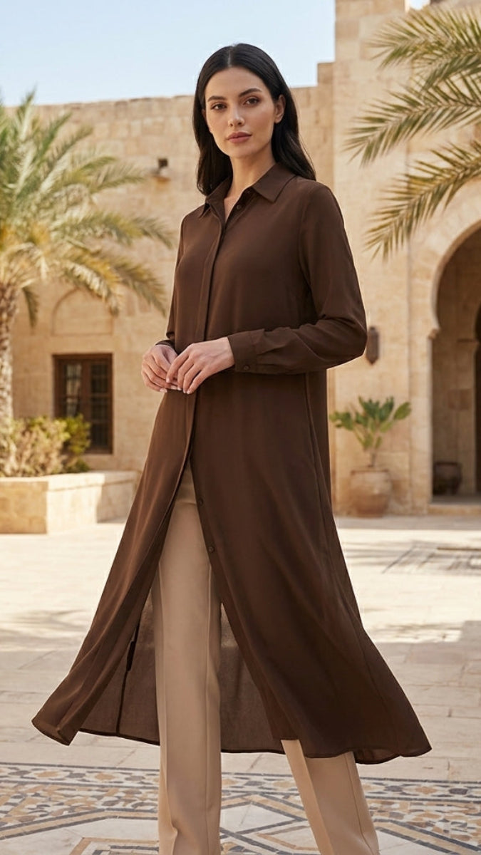 Woman in a brown dress standing in an outdoor courtyard with palm trees and architectural elements.