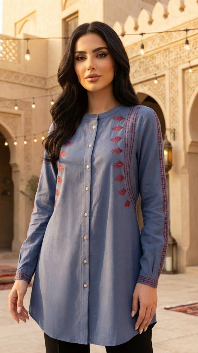 Woman wearing a blue embroidered dress in an outdoor courtyard setting