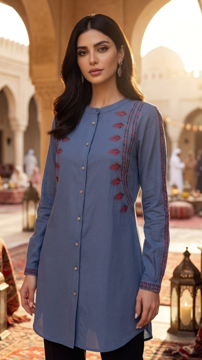 Woman in a blue embroidered dress standing in a decorative indoor setting with arches and lanterns.