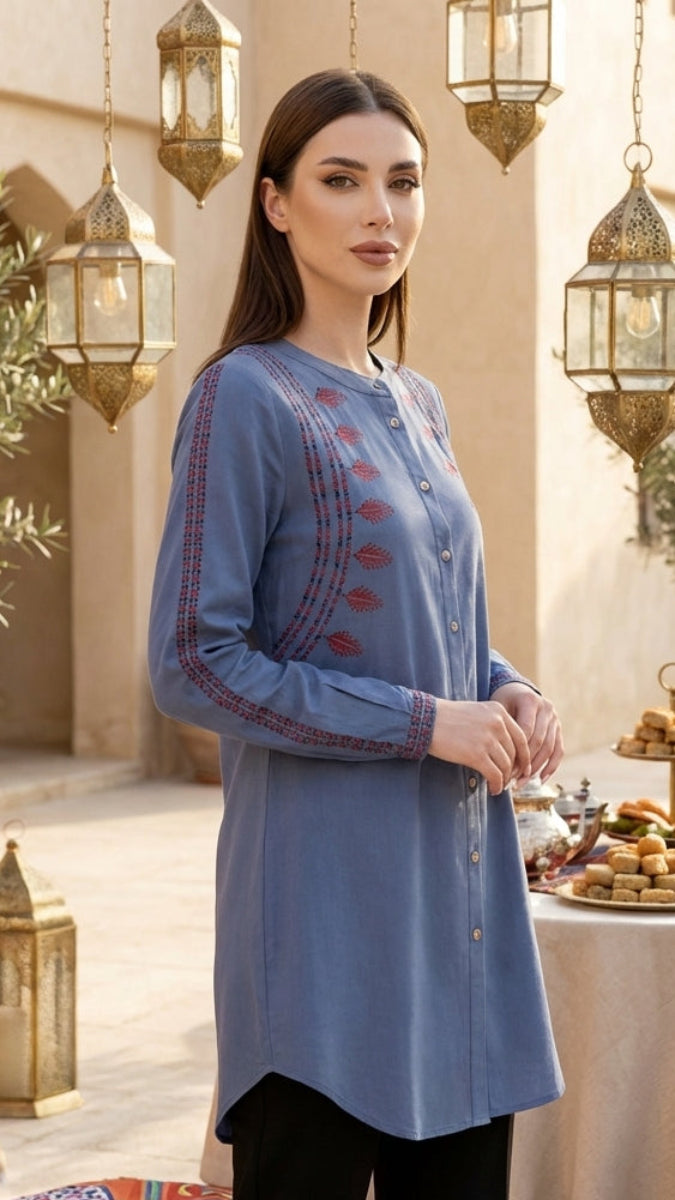 Woman in a blue embroidered dress standing in an outdoor setting with lanterns and a table with food.