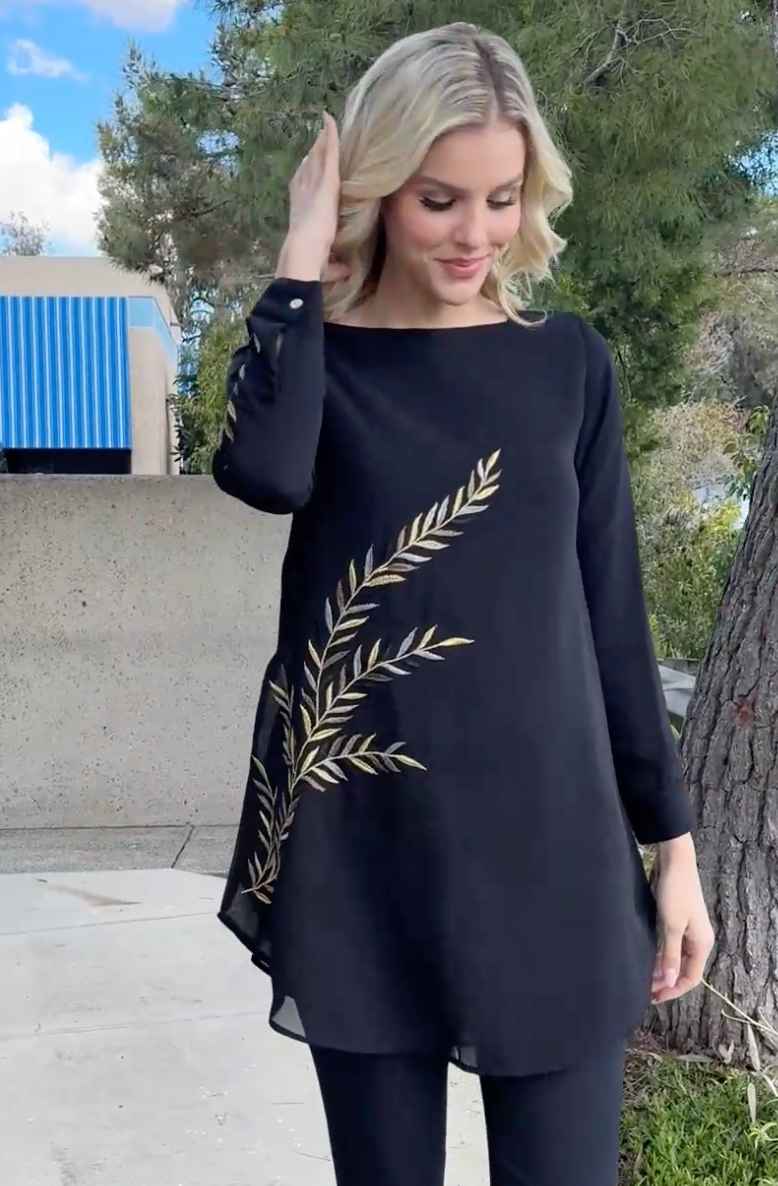Woman looking down wearing Baraka tunic in Black. 