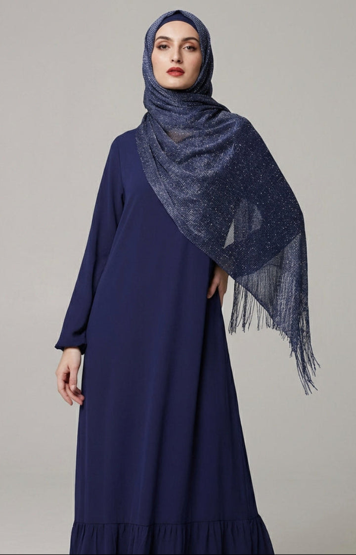 Woman wearing a long navy dress with a matching hijab on a gray background