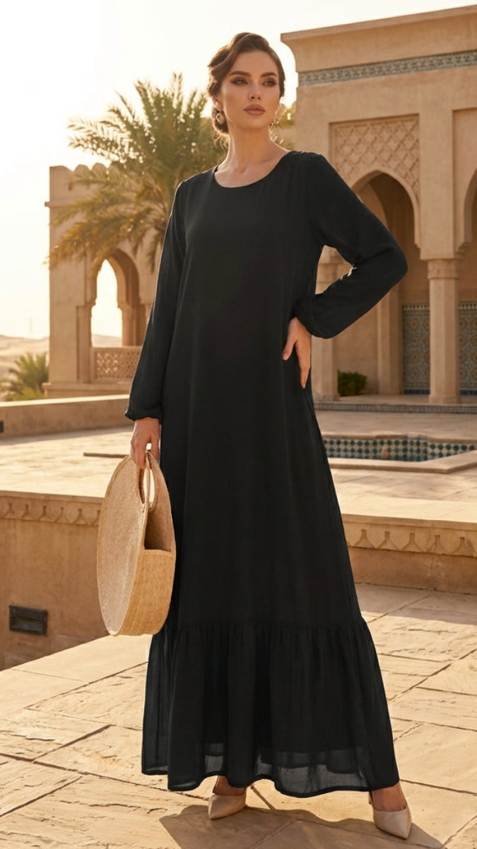 Woman in a black dress standing in front of an architectural building with palm trees.