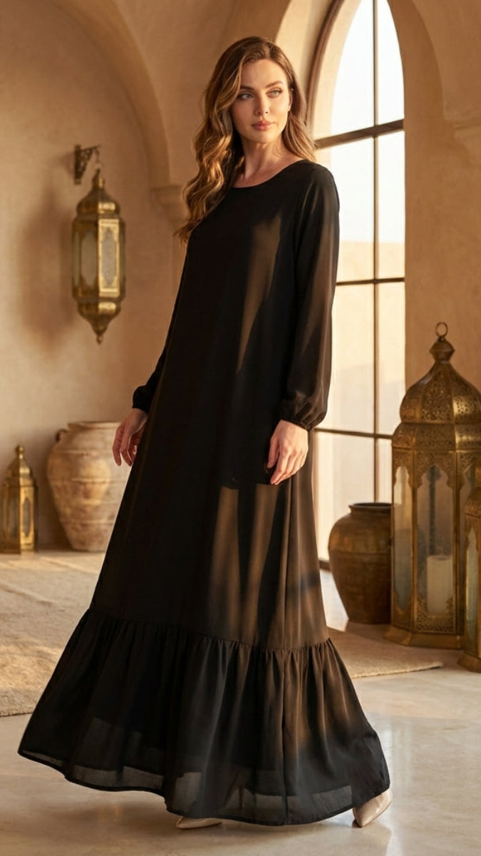 Woman in a black dress standing in a sunlit room with decorative lanterns.