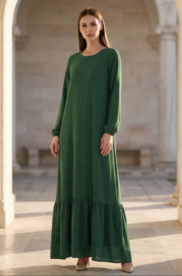 Woman wearing a green dress standing in a sunlit architectural setting