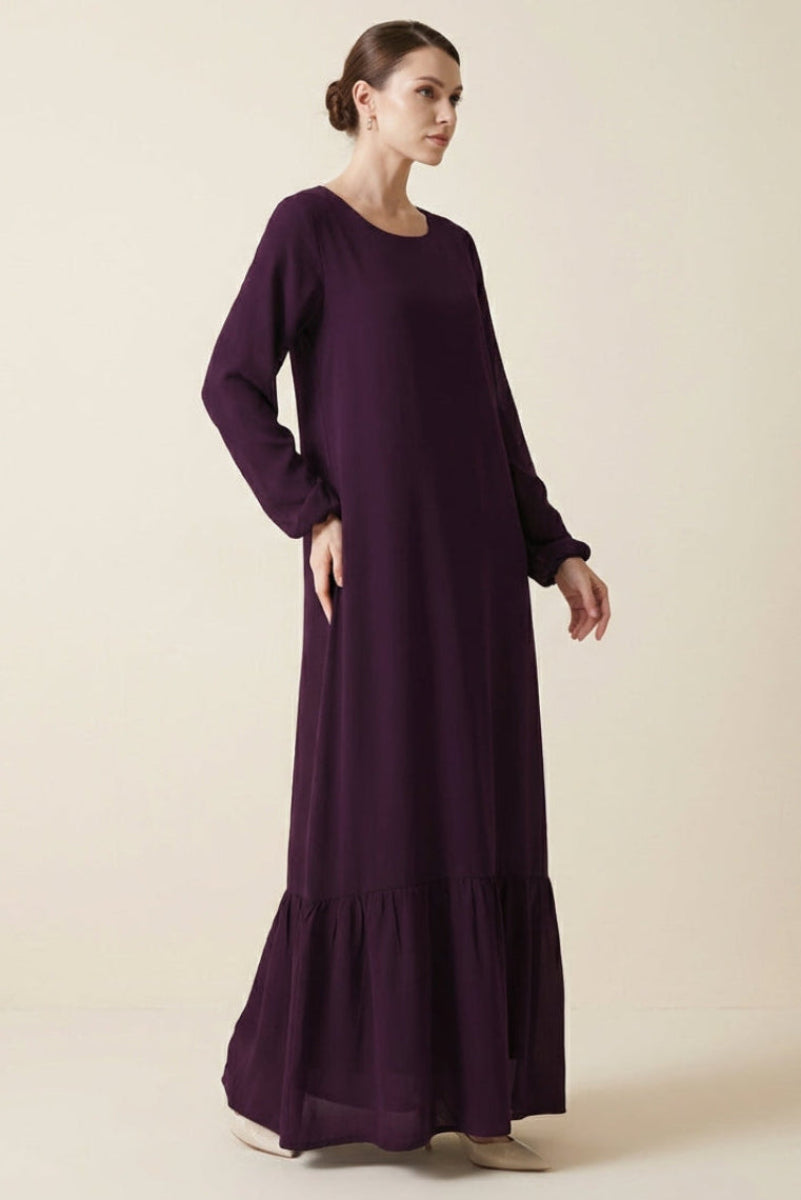Woman wearing a long purple dress on a beige background