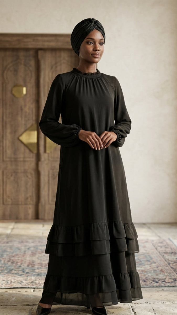 Woman wearing a black dress standing in a room with wooden door and light floor.