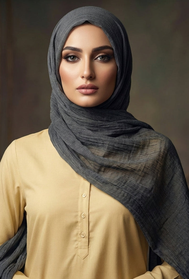 Woman wearing a dark hijab and beige top against a blurred background