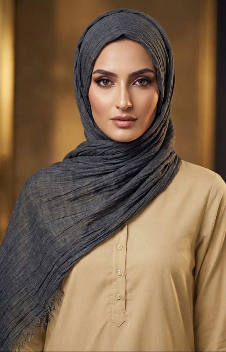 Woman wearing a dark hijab and beige shirt against a blurred background