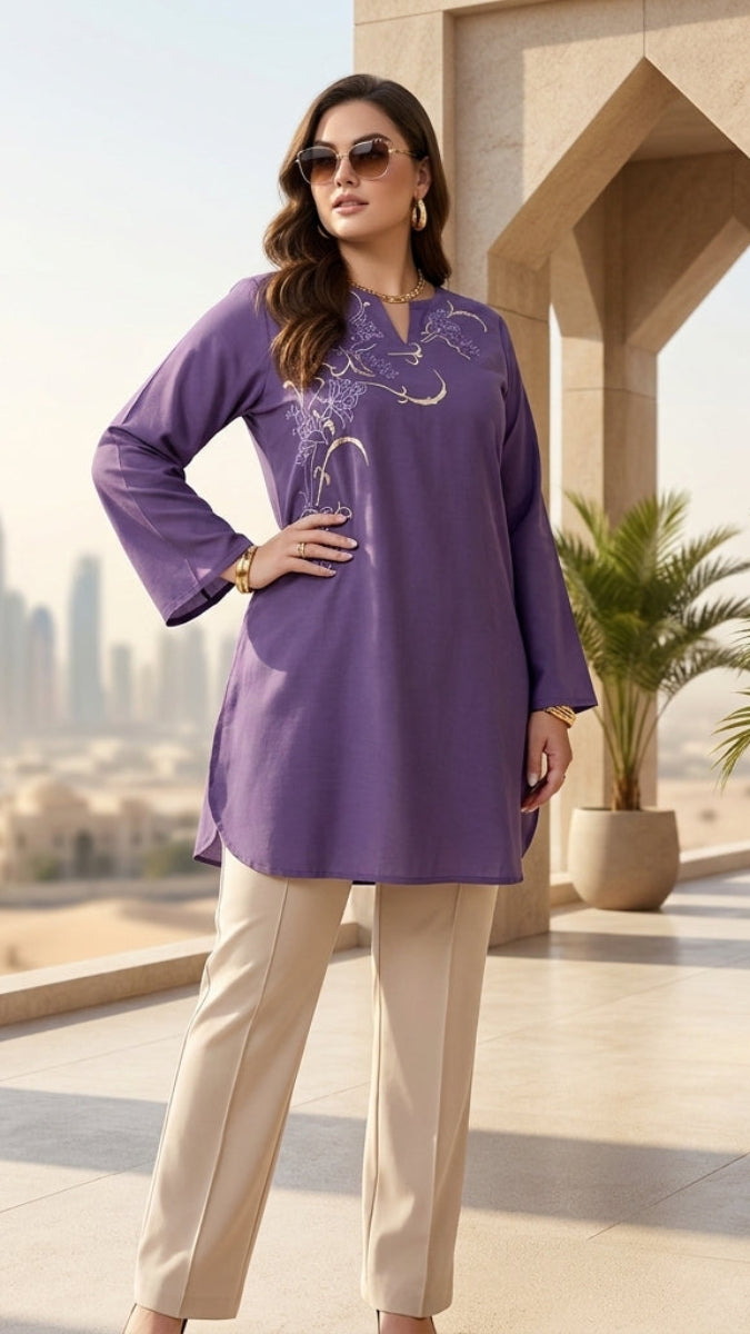 Woman in a purple top and beige pants standing in front of a cityscape with modern buildings.