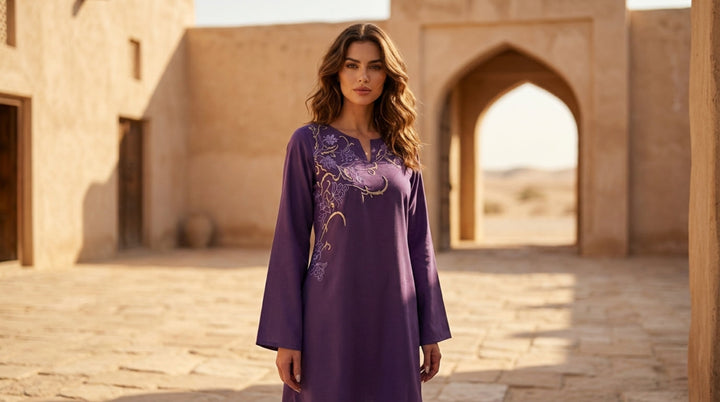Woman in a purple dress standing in an arched stone building with a warm glow.