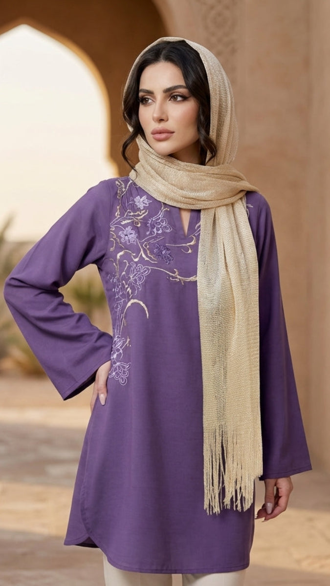 Woman wearing a purple dress with floral patterns and a beige scarf in an outdoor setting.