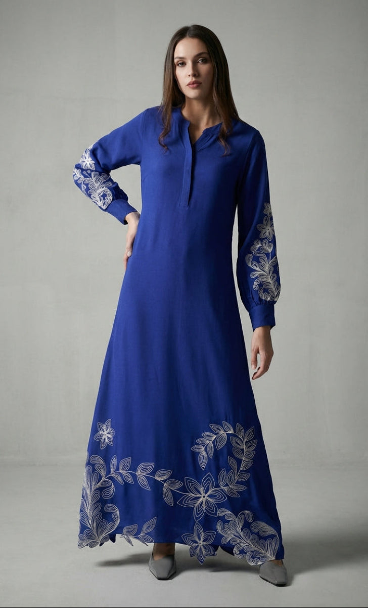 Woman wearing a blue dress with floral embroidery on a gray background