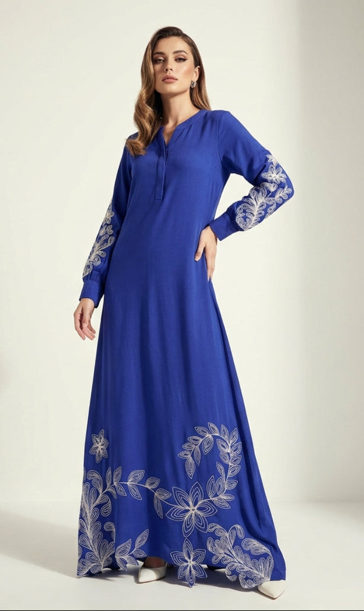 Woman wearing a blue dress with white floral embroidery on a white background