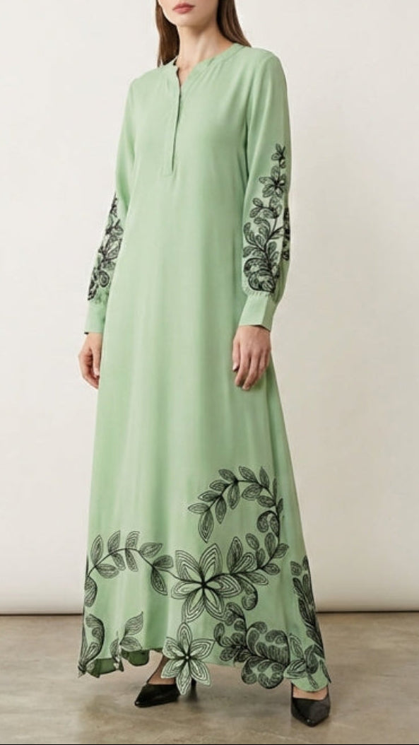 Woman wearing a light green dress with floral patterns on a plain background