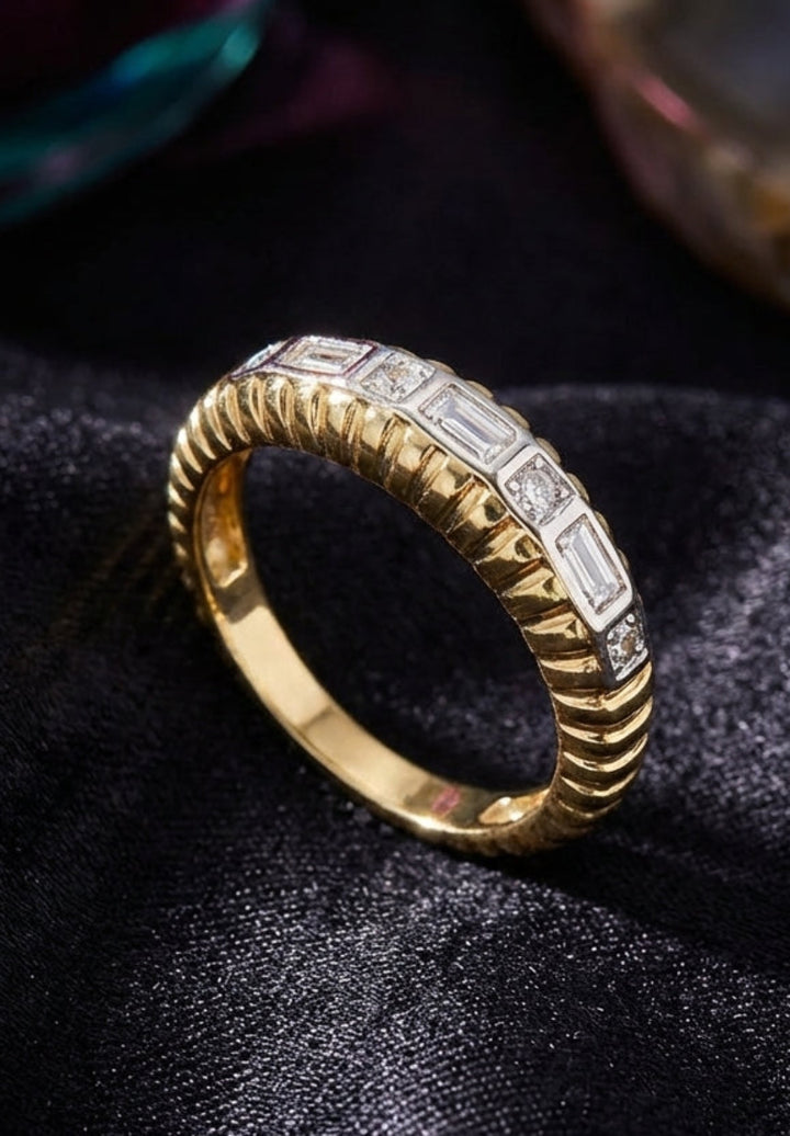 Gold ring with diamond accents on a dark fabric background