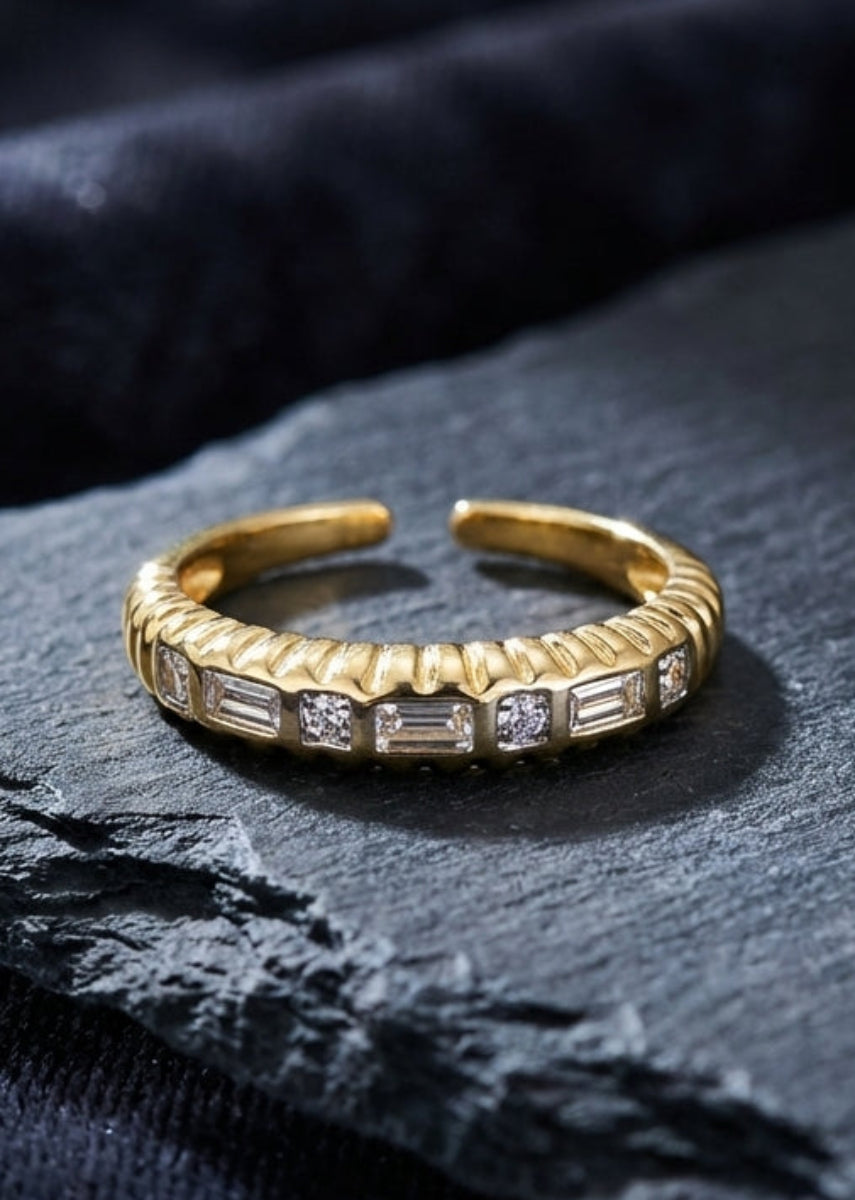 Gold ring with embedded stones on a dark stone surface